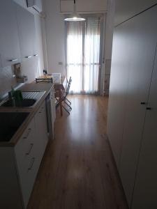 a kitchen with white cabinets and a wooden floor at LaSpiaggia21 in Marotta