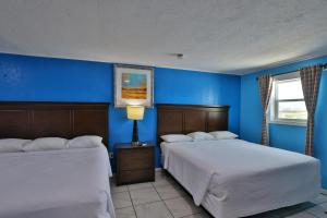 two beds in a room with blue walls at Monterrey Motel Padre Island, Corpus Christi BY OYO in Padre Island