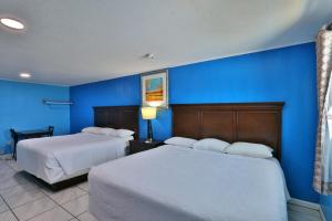 two beds in a room with blue walls at Monterrey Motel Padre Island, Corpus Christi BY OYO in Padre Island