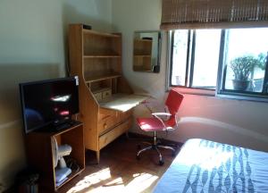 a bedroom with a desk and a television and a chair at Pascua 2-baño compartido in Santiago