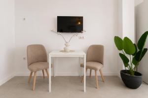 two chairs and a table with a tv on a wall at Sanchis Studios in Alicante