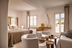 a bedroom with a bed and chairs and a table at Hotel Adonis in Mikonos