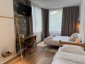 a hotel room with two beds and a desk with a computer at Hotel Vellezrit Guri in Theth