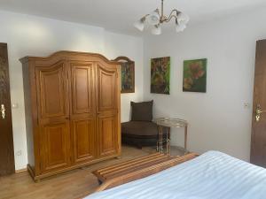 a bedroom with a large wooden cabinet and a chair at Gästehaus Wildfein in Wilnsdorf