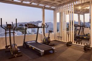 a gym with several exercise bikes in a room with a window at Hotel Adonis in Mikonos