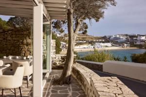 a patio with a table and chairs and a tree at Hotel Adonis in Mikonos