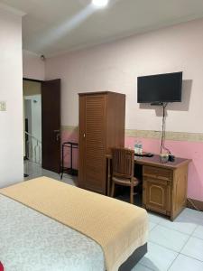 a bedroom with a bed and a desk and a tv at Wisma Pakuan Syariah Hotel in Bogor