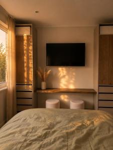 a bedroom with a bed and two stools under a television at Erftlodges L1 in Bad Münstereifel