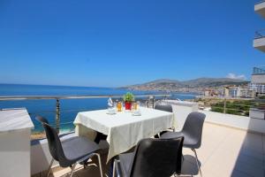 a table on a balcony with a view of the ocean at Elena's Hotel & apartments in Sarandë