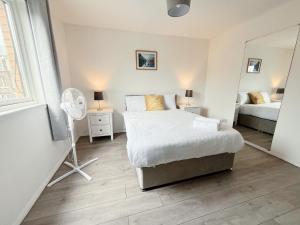 a white bedroom with a bed and a fan at The Easter Suites with free parking in Edinburgh
