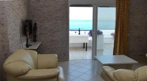 a living room with white furniture and a view of the ocean at Elena's Hotel & apartments in Sarandë