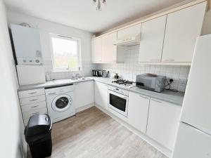 a kitchen with white cabinets and a washer and dryer at The Easter Suites with free parking in Edinburgh