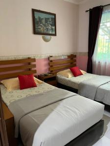 a bedroom with two beds with red pillows at Wisma Pakuan Syariah Hotel in Bogor