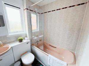 a bathroom with a pink tub and a sink at The Easter Suites with free parking in Edinburgh +26 photos