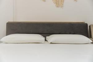 two pillows on a bed with a gray headboard at NooN Apartment | Sofo Duni by PikHost in Dhërmi
