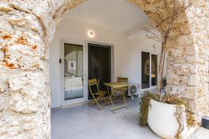 a patio with a table and chairs and a stone wall at NooN Apartment | Sofo Duni by PikHost in Dhërmi