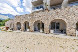 a stone building with arches and a patio at NooN Apartment | Sofo Duni by PikHost in Dhërmi