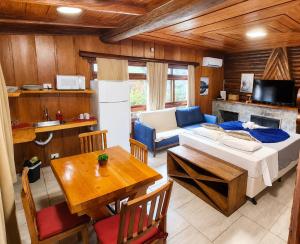 a living room with a bed and a table and a couch at Empório reserva da serra - Opções de chalés e Hidromassagem in Campos do Jordão