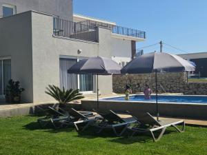 a group of lawn chairs and umbrellas next to a pool at Villa Oaza in Bar