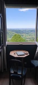 a table and chairs in a room with a large window at La Maison d'Osquich in Musculdy