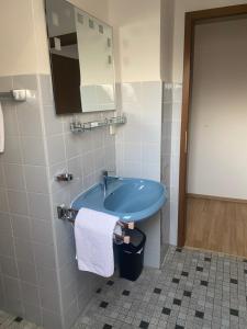 a bathroom with a blue sink and a mirror at Gästehaus Wildfein in Wilnsdorf +8 photos