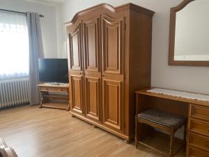 a room with a large wooden cabinet and a desk at Gästehaus Wildfein in Wilnsdorf