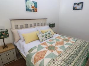 a bedroom with a bed with a quilt on it at Daffodil Cottage in Treorky