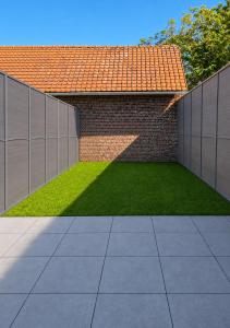 a garden with a brick wall and a green lawn at Studio between city and countryside in Lompret