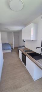 a kitchen with white cabinets and a bed in a room at Studio between city and countryside in Lompret