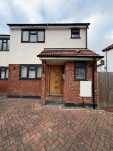 a brick house with a yellow door on a brick driveway at Stylish Charming London Flat Ruislip -Free Parking in Ruislip