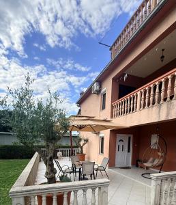 a house with a patio with chairs and an umbrella at SARA in Ðuranovići