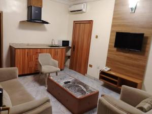 a living room with a couch and a table and a tv at Marrisson Residence in Abuja