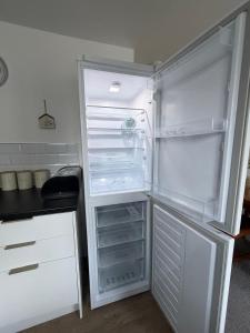 an empty refrigerator with its door open in a kitchen at Stylish Charming London Flat Ruislip -Free Parking in Ruislip +19 photos