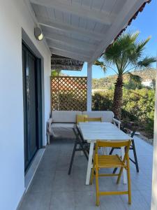 a white table and chairs on a patio with a palm tree at Pebble Home in Yialós