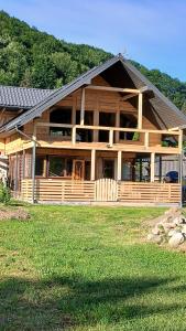 a large wooden house on a grass field at Садиба Федорчуків За рікою1 in Sheshory