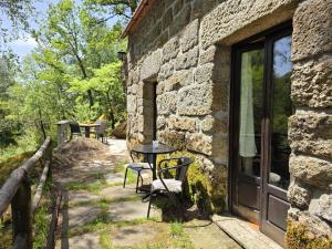 a patio with a table and chairs next to a stone building at Moinhos do Poço Verde in Castro Laboreiro