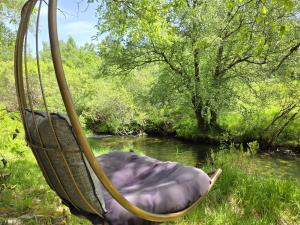 a hammock hanging over a river next to a creek at Moinhos do Poço Verde in Castro Laboreiro