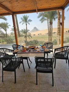 a table and chairs in a patio with palm trees at Dahshur Pyramids View Inn in Giza