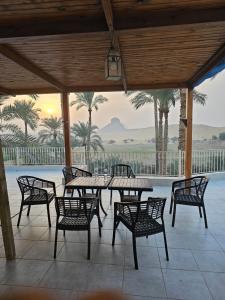 a patio with a table and chairs and palm trees at Dahshur Pyramids View Inn in Giza
