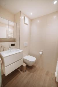 a white bathroom with a toilet and a sink at ALPEN STUDIO - moderne Ferienwohnung mit Bergblick & Südterrasse in Bad Hindelang in Bad Hindelang