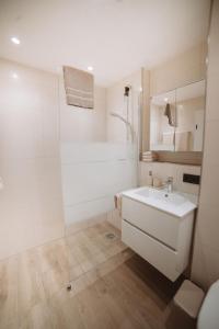 a white bathroom with a sink and a shower at ALPEN STUDIO - moderne Ferienwohnung mit Bergblick & Südterrasse in Bad Hindelang in Bad Hindelang
