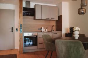 a kitchen with white cabinets and a table with chairs at ALPEN STUDIO - moderne Ferienwohnung mit Bergblick & Südterrasse in Bad Hindelang in Bad Hindelang