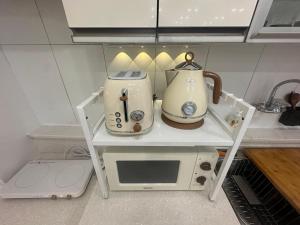 a microwave and a tea kettle on a shelf in a kitchen at Lagom villiage in Paegun-dong