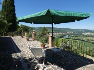 a green umbrella and two chairs on a balcony at Scappo in Umbria, L'antico casale in Narni