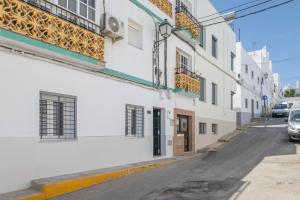a street with white buildings and a car parked on the street at Casa Parque Benavente Conil in Conil de la Frontera