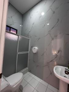 a bathroom with a shower and a toilet and a sink at Hostal Café Tiana in Latacunga