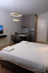 a large white bed in a room with a kitchen at Centralin Apartotel in Tirana