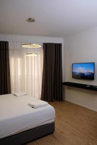 a bedroom with a bed and a flat screen tv at Centralin Apartotel in Tirana