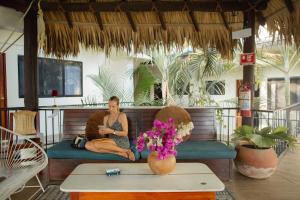 a woman sitting on a couch on a porch at Punta Dreams in Brisas de Zicatela