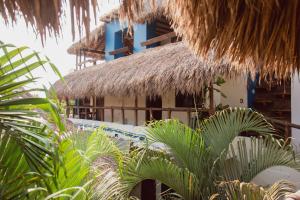 a building with a thatched roof and some palm trees at Punta Dreams in Brisas de Zicatela